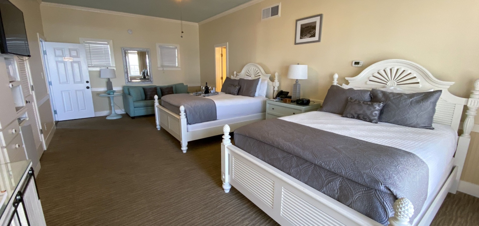 A coastal hotel suite with two double beds and a sofa