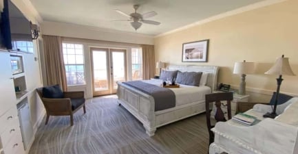 A coastal hotel suite with a king bed, veranda, and ocean views
