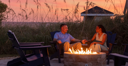 Couple at fire pit with a sunset backdrop