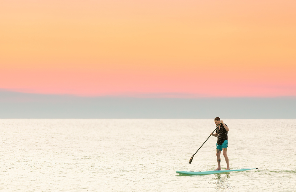 Paddleboarder under orange sky