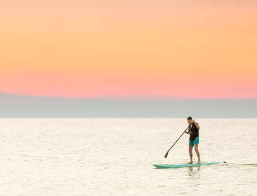 Paddleboarder under orange sky
