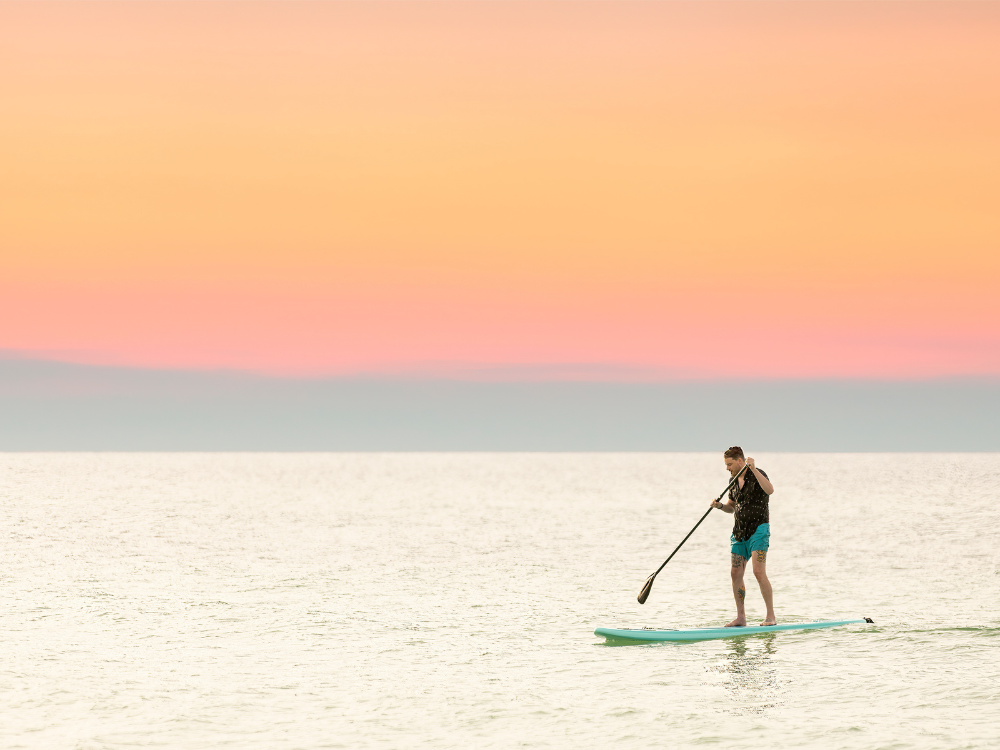 Paddleboarder under orange sky